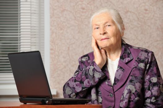 The elderly woman in front of the laptop. A photo in a room