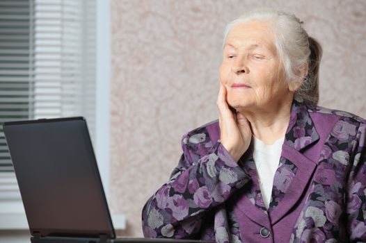 The elderly woman in front of the laptop. A photo in a room