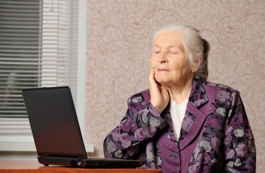 The elderly woman in front of the laptop. A photo in a room