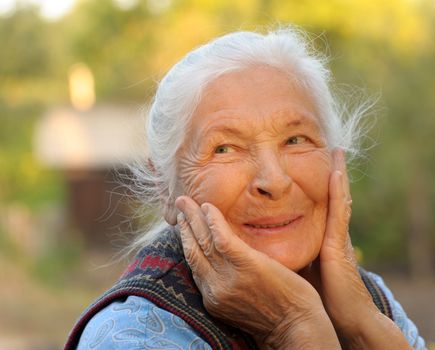 Portrait of the laughing elderly woman. A photo on outdoors