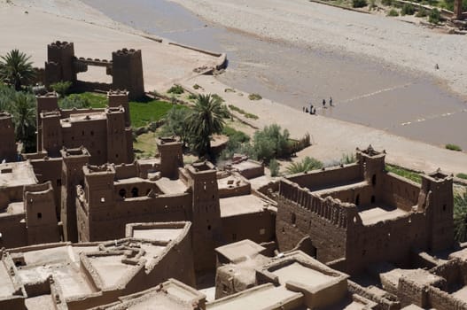 Kasbah Ait Benhaddou fortified city. View from the top  with tourists who cross the river. A UNESCO World Heritage Site. Best of Morocco.