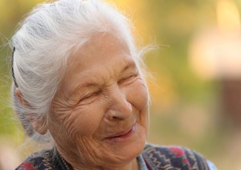 Portrait of the laughing elderly woman. A photo on outdoors