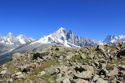 View of the Mont-Blanc massif from the mountain behind lots of stones by beautiful weather, Chamonix, France