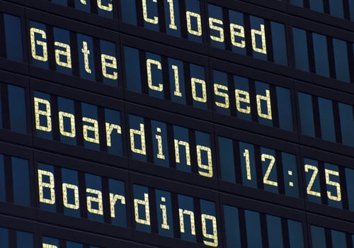 Airport information board, gate closed and boarding announcement.