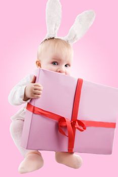 Baby in bunny costume with present on pink