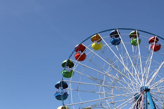 Ferris wheel close up over blue sky.