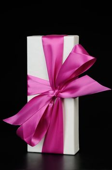 Gift box with a big pink bow. On a dark background.