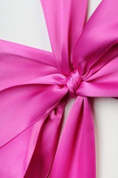 Gift box with a big pink bow close up. On a dark background.