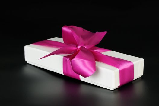 Gift box with a big pink bow. On a dark background.