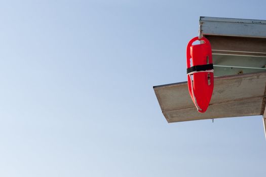 Red Rescue Tube hanging on Lifeguard Tower with blue sky