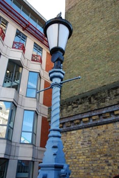 Vintage streetlamp between modern  office building and old brick wall