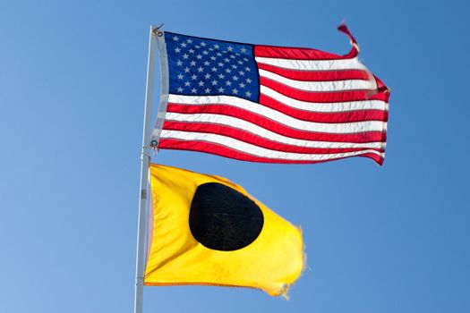 American Flag and Black Ball Flag in front of a blue sky