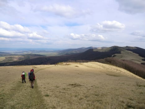 Travellers go on the way to a mountain ridge in Carpathians