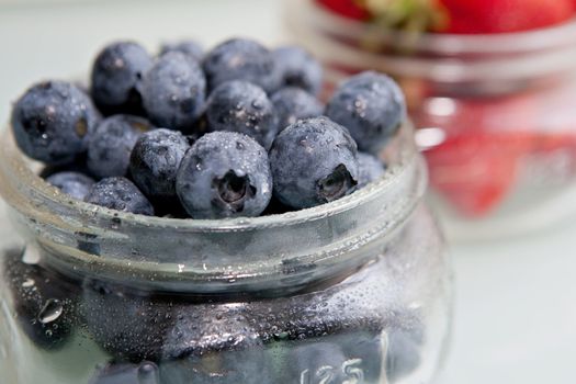 Bunch of fresh, misty blueberries with Strawberries in the Background