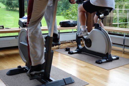 Closeup on legs of people cycling in fitness center