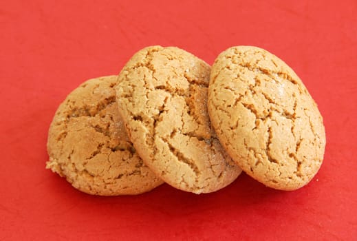 three fresh appetizing oatmeal cookies over red background