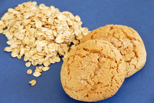 two fresh appetizing oatmeal cookies over blue background