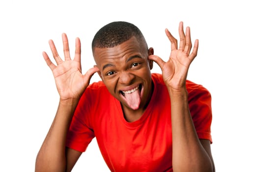 Young man with humorous funny expression sticking tongue out and hands next to face playing peekaboo, isolated.