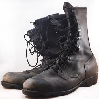 Used black leather combat boots in front of white background