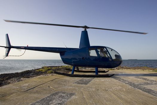 Helicopter Robinson 44 landed on an helipad in front of the ocean