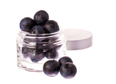 Fresh blueberries in a glass beauty cream jar. Isolated over white with clipping path.