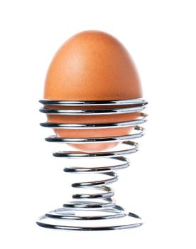 A delicious brown boiled egg in a stainless steel egg cup. Isolated over white with clipping path.