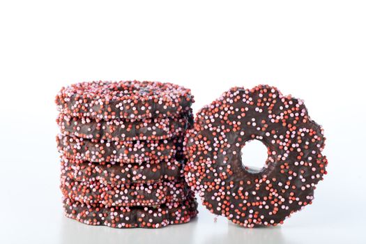 Cookies dipped in chocolate and covered with pink sprinkles on a white background.