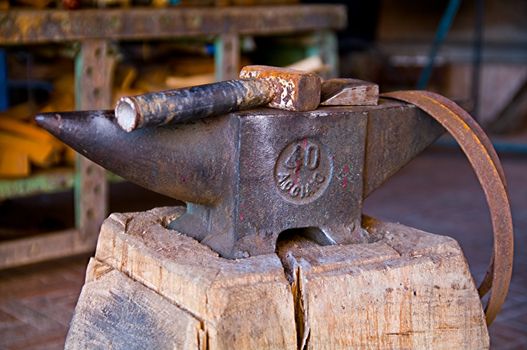 A rusted sledge hammer on a iron anvil,  and a ring to be mounted on a barrel.