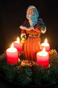 Christmas advent wreath with burning candles and Santa Claus
