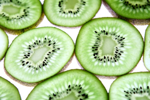 Detail view of kiwi slices backlighted over white background. 