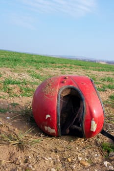 Broken red helmet on a rural field