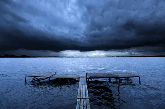 Old pier over dramatic story clouds. Zalew Zegrzynski, Poland.