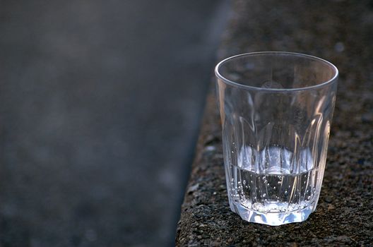 Nearly empty glass of sparkling water on stone step
