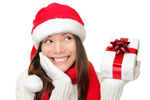 Santa girl holding christmas gift. Young happy woman in santa hat looking sideways showing Christmas present isolated on white background. Beautiful cute young santa woman.