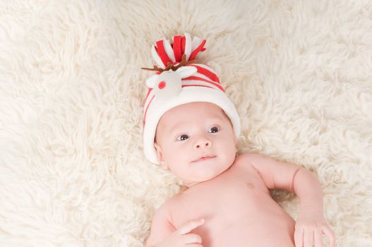 Newborn baby in chritstmas hat lies on fur