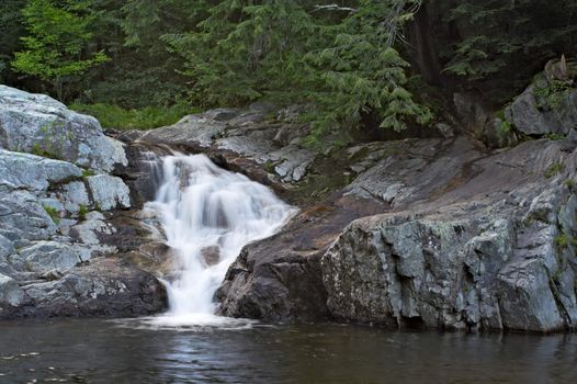 A waterfall surrounded by rocks and trees.