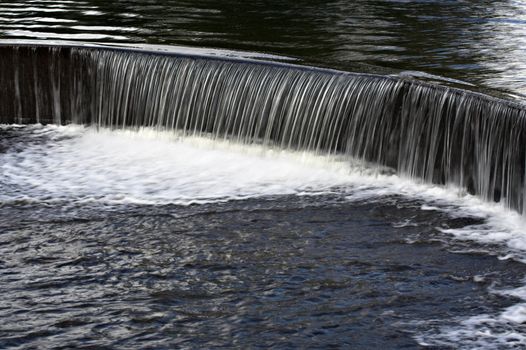 Water flowing over a manmade dam in a lake