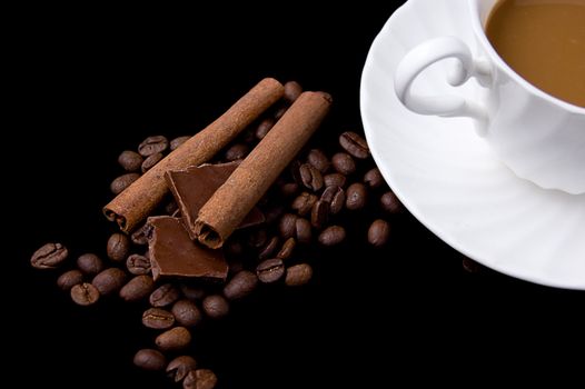Cup of cappuccino, coffee beans, cinnamon and chocolate on balck