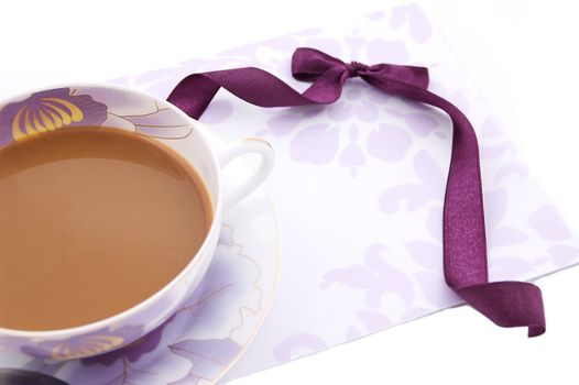 Cup of cappuccino, blank note and violet ribbon