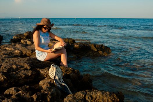 Woman ejoying a book with her feet in the water