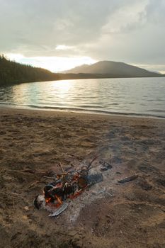 Small campfire on remote lake shore in northern Canada.