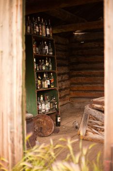 Collection of empty liquor bottles on shelf on ruin of log cabin of historic Big Salmon Trading Post, Yukon Territory, Canada.