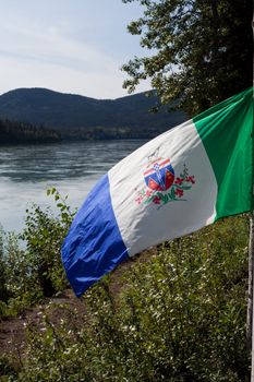 Wind blowing Yukon Territorial flag with Yukon River flowing in background