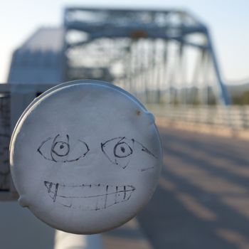 funny face graffiti on railing of steel bridge