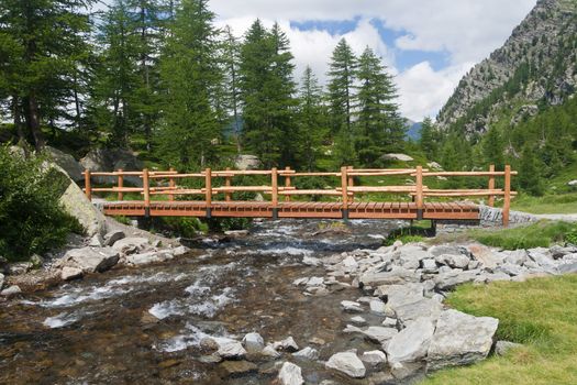 small bridge over an alpine creek in Arpy valley, Aosta, Italy