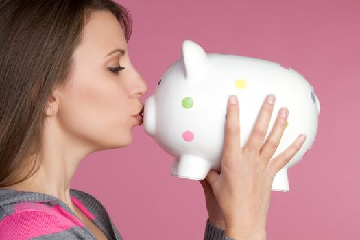 Pretty girl kissing piggy bank