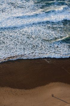 View of a couple walking down the beach shoreline.