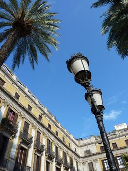 Buildings, palm trees and street lamps at the Place Reial in Barcelona, Spain, by beautiful weather