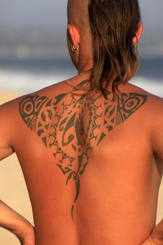 The young man with a beautiful tattoo on a coast of ocean