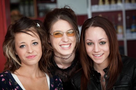 Three young cute teen friends smiling in a cafe